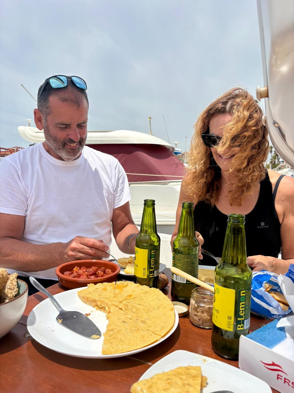 A couple enjoying homemade tortilla, tapas and cold beers aboard the sailboat in Tarifa harbour