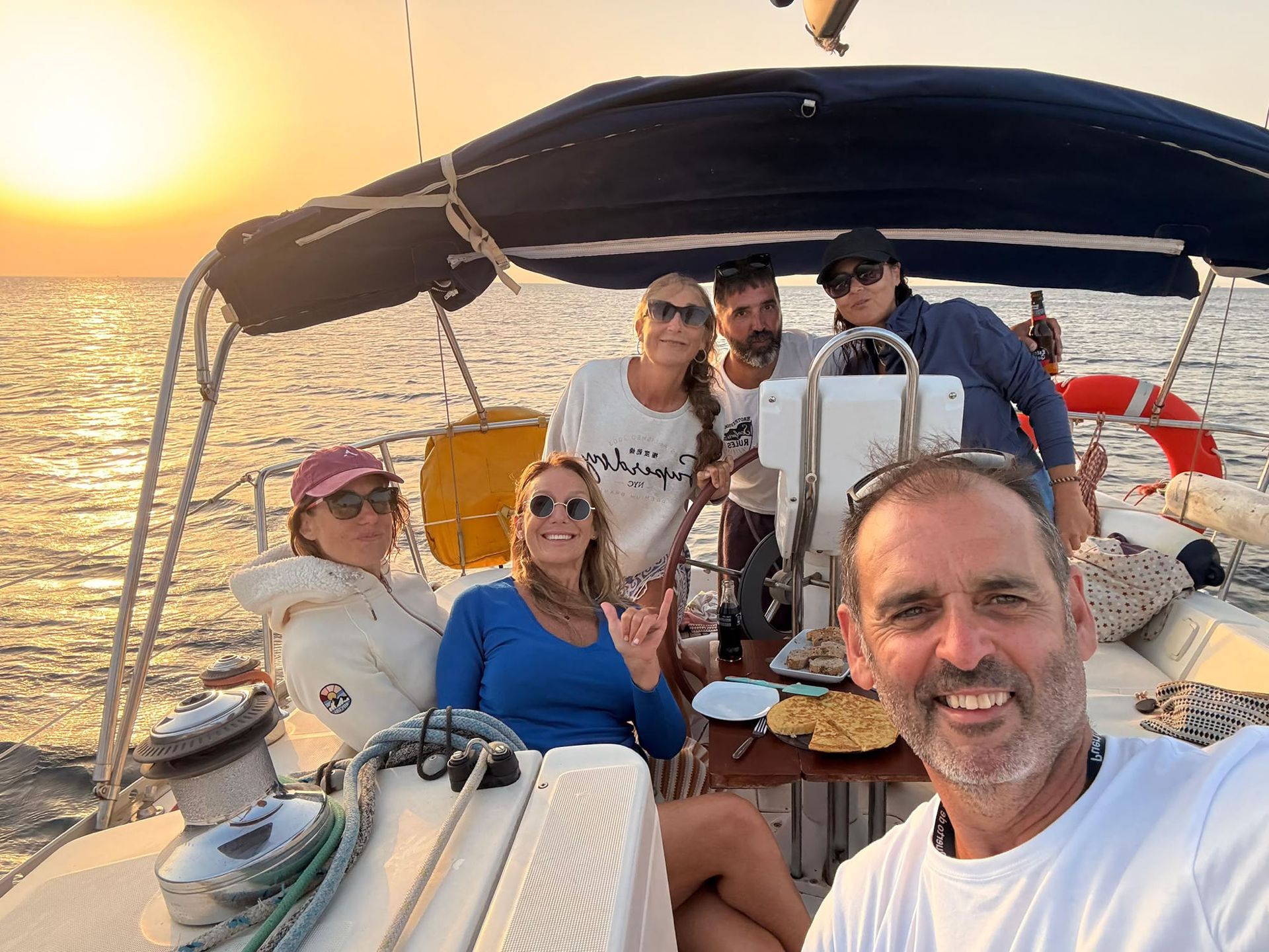 A group of guests and the skipper at sunset sharing Spanish omelette on board