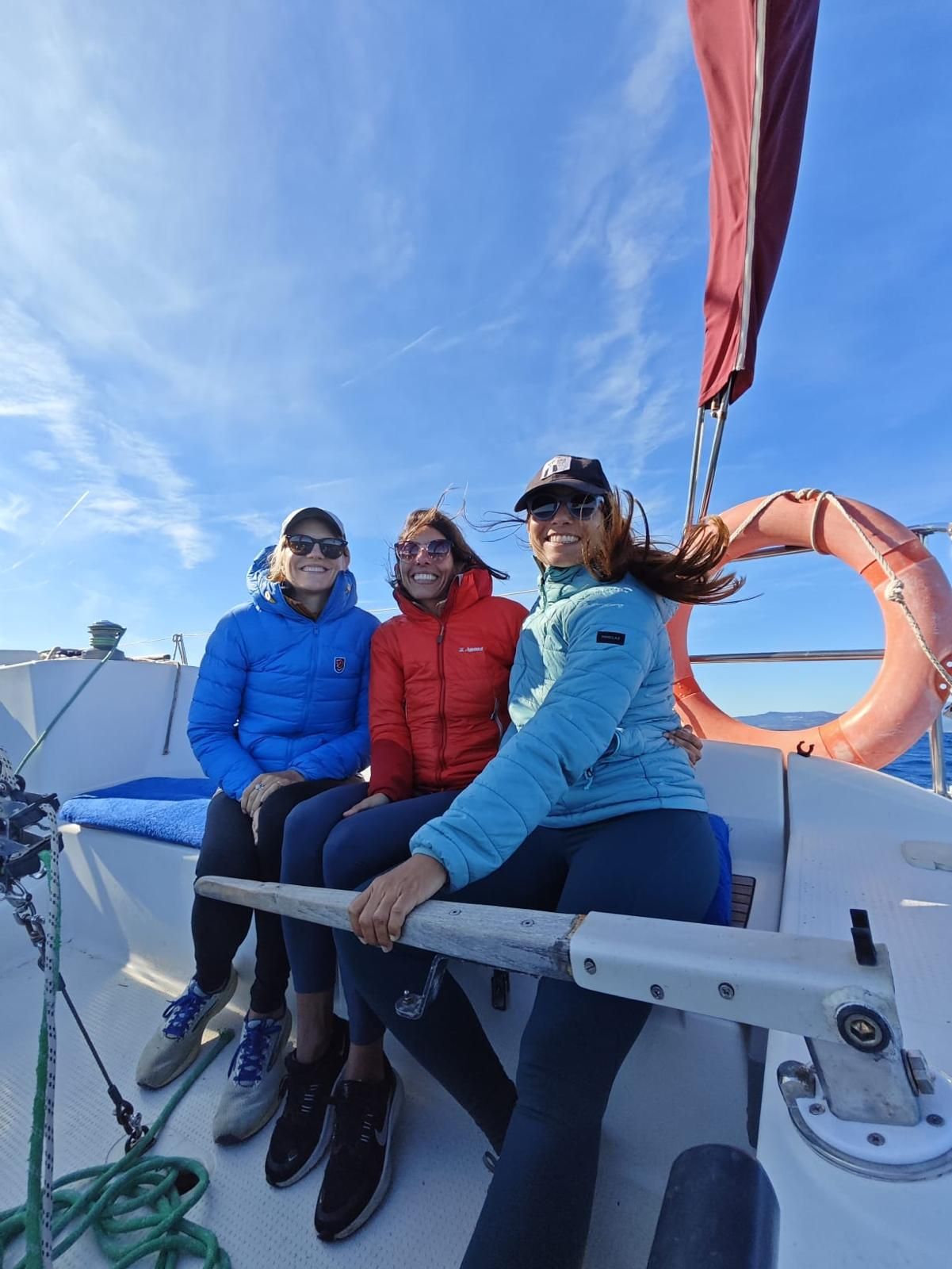 Three friends laughing on the sailboat deck on a sunny day out on the Strait